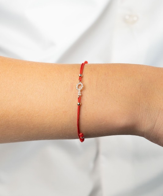 Red string bracelet with a gold pendant and zirconium