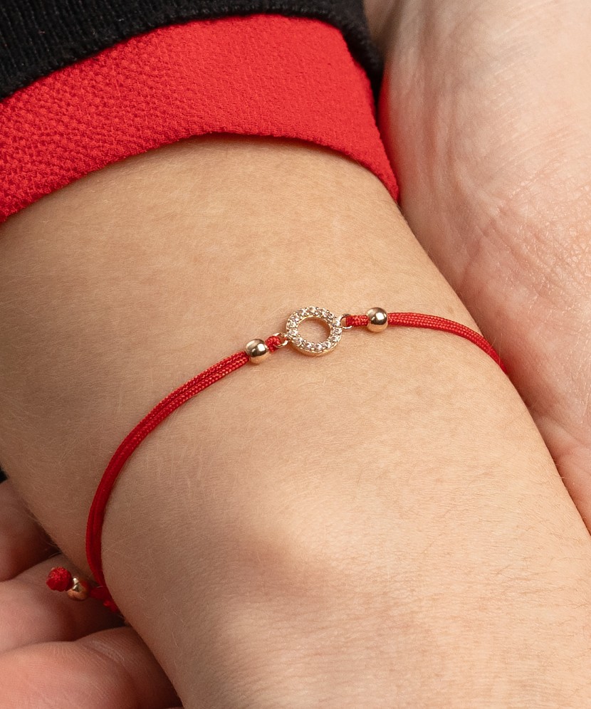 Red string bracelet with a gold pendant and zirconium