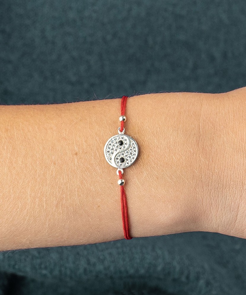 Red string bracelet with a silver pendant with zirconium