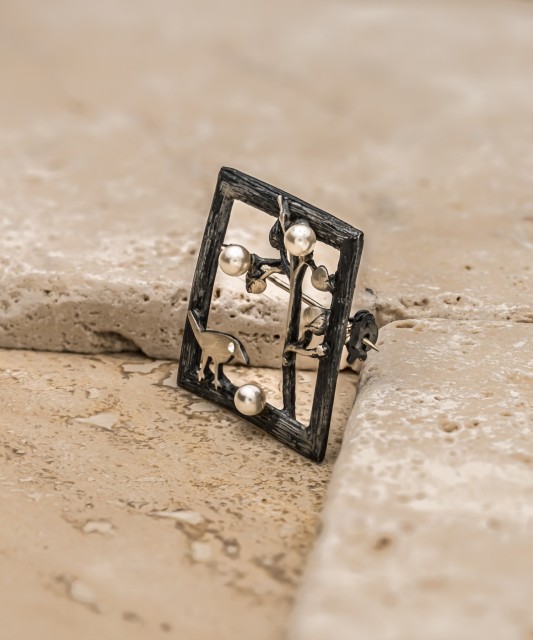 Hopeinen rintaneula helmellä