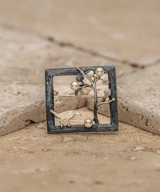 Hopeinen rintaneula helmellä